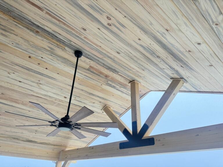 Wooden ceiling with a stylish ceiling fan, showcasing a covered patio design for outdoor living in Foxfield, Colorado.